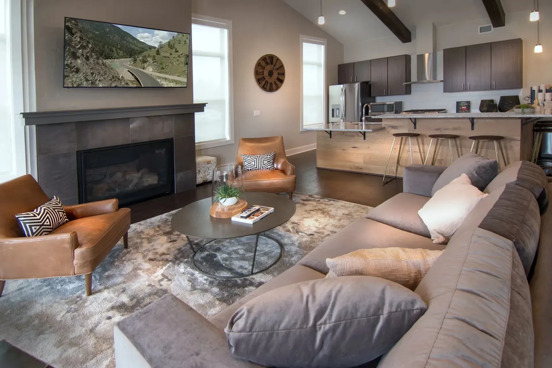 Living room with a fireplace, sectional sofa, armchair, and kitchen island with bar stools.
