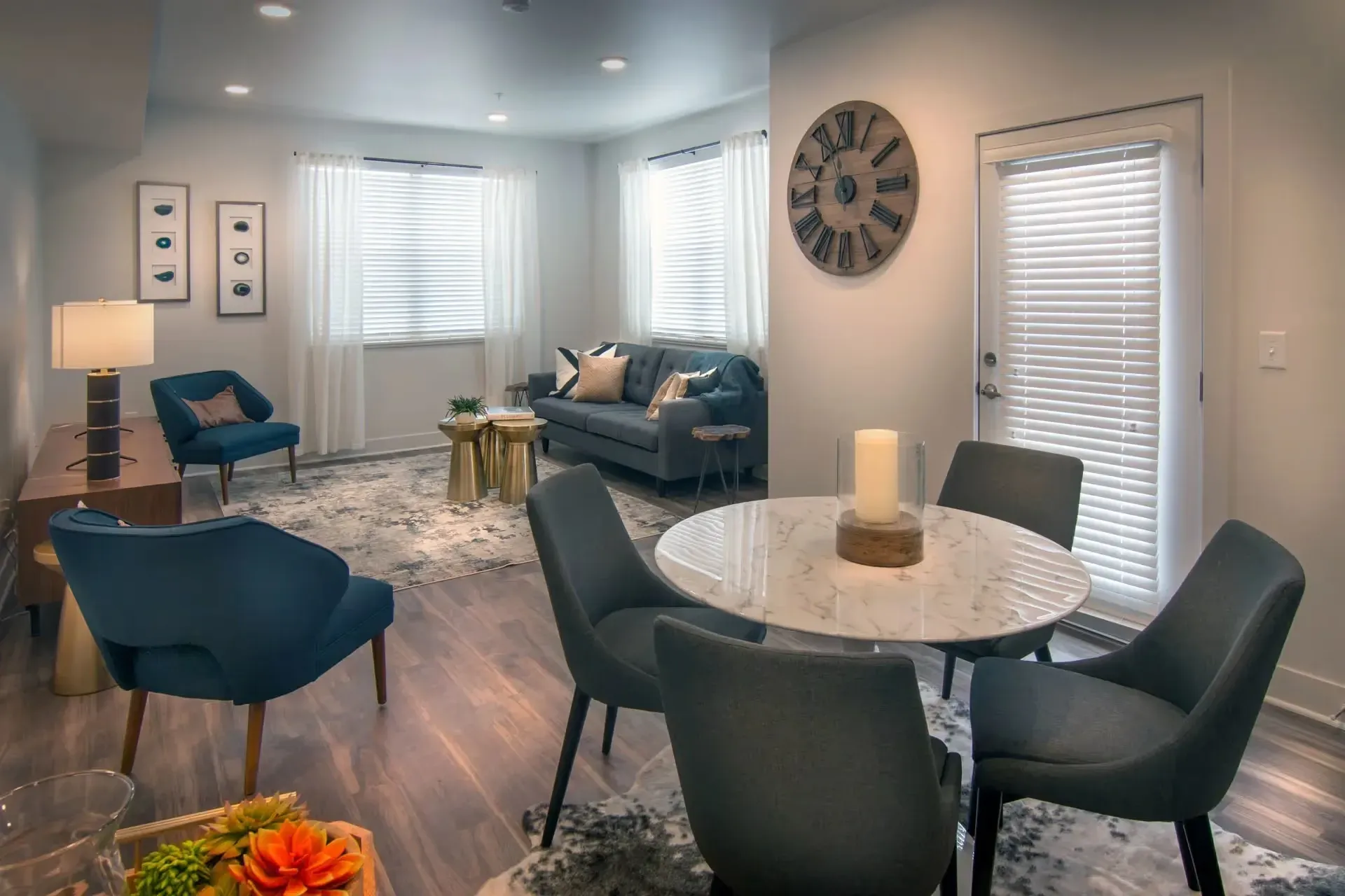Living and dining area with a sofa, chairs, dining table, and large clock.