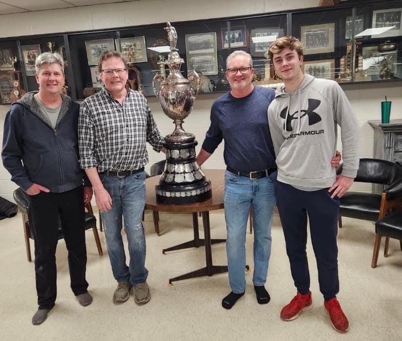 A group of people posing for a picture in front of a trophy