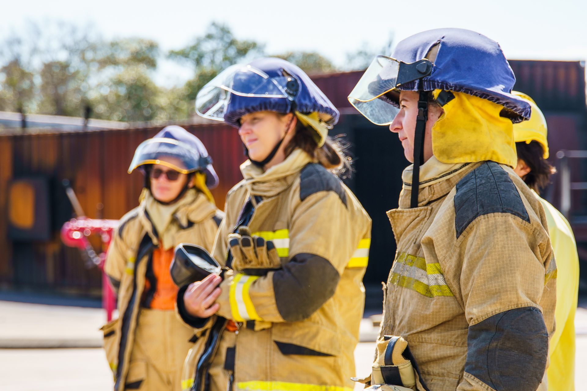 Firefighters in yellow gear and helmets stand outside, ready for action.