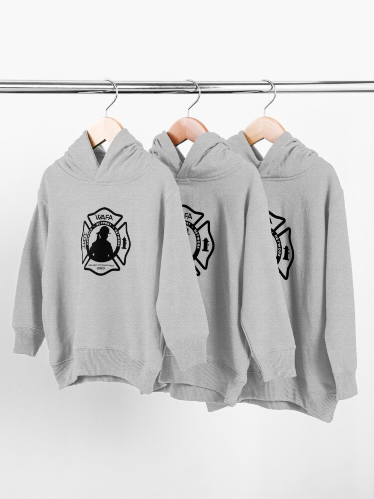 Three gray children's hoodies hanging on a rod, each with a black firefighter emblem on the chest.