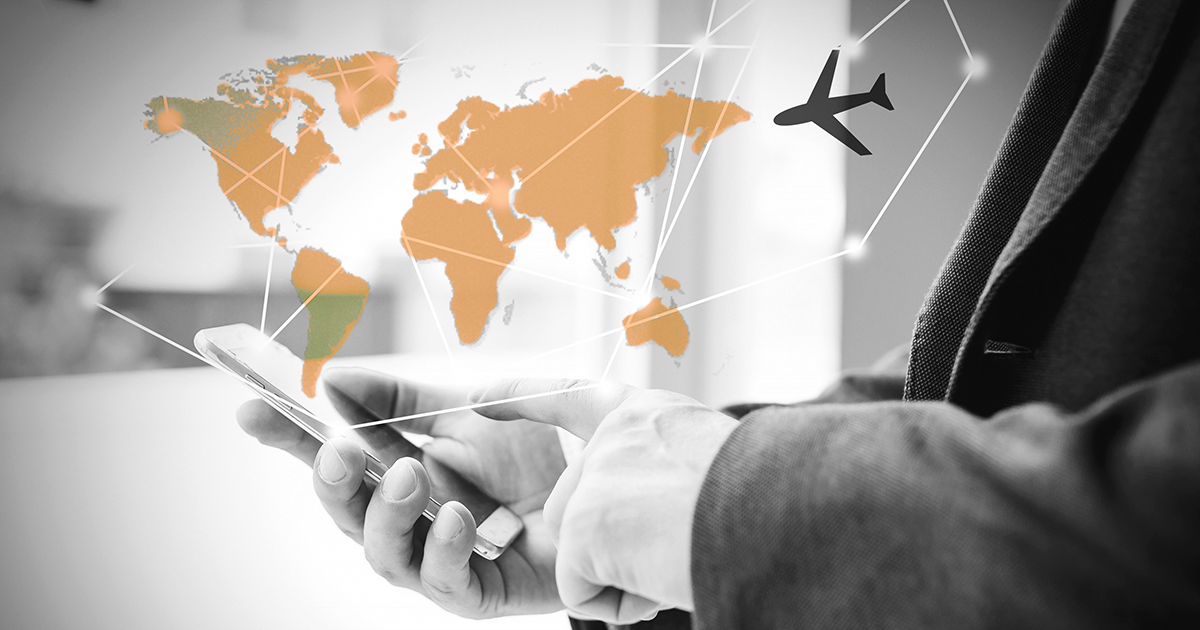 Image of a man on phone looking at business travel with global map showing above