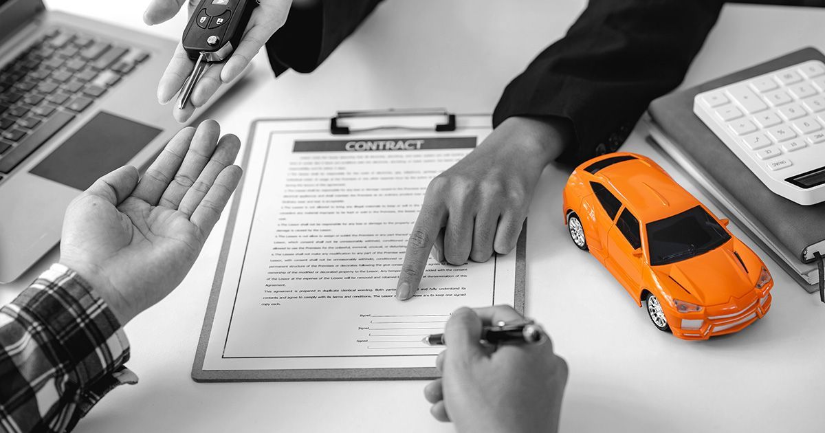 Black and white image with orange toy car on table