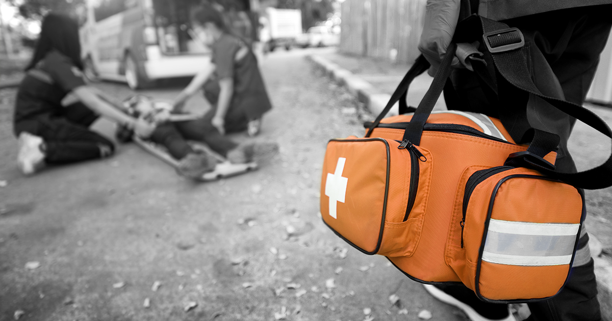Scene of an accident with person lying on floor and a member of the ambulance holding a medical bag