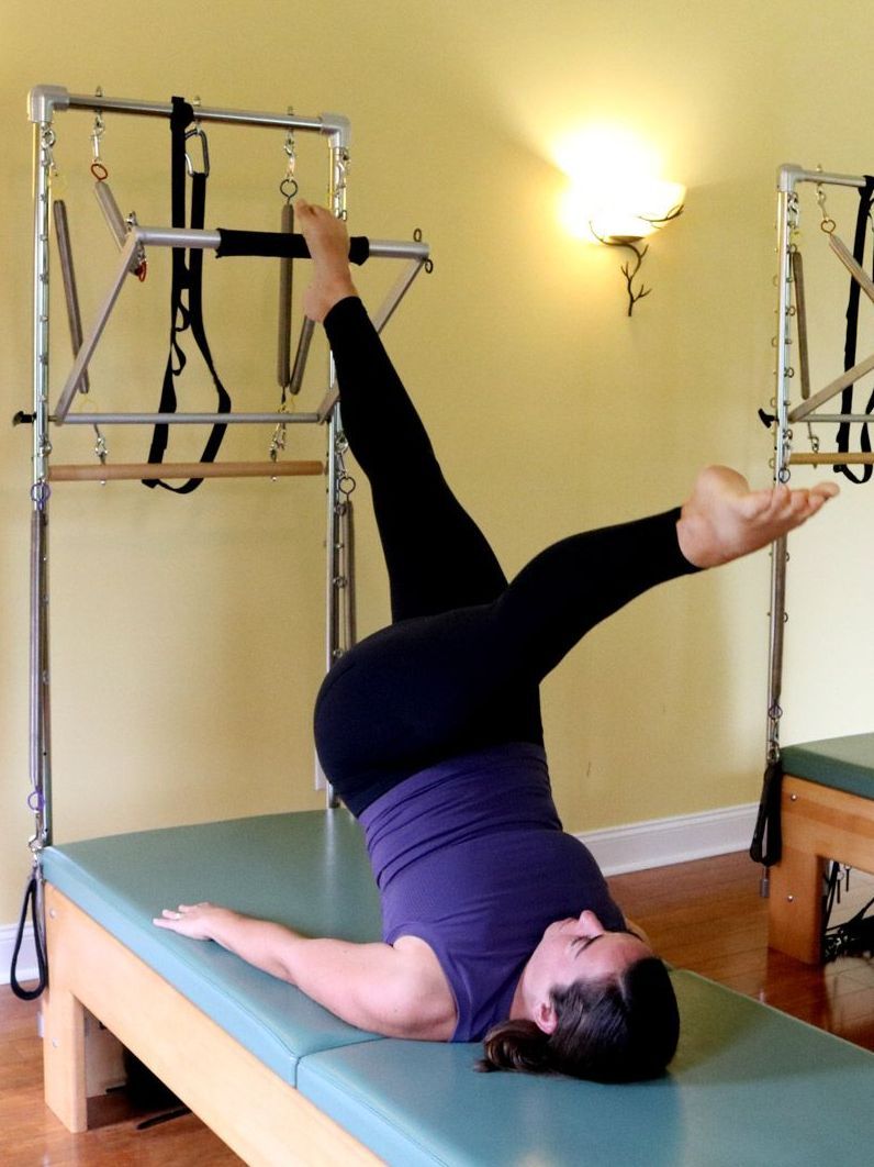 a woman is laying on a pilates equipment with her legs up