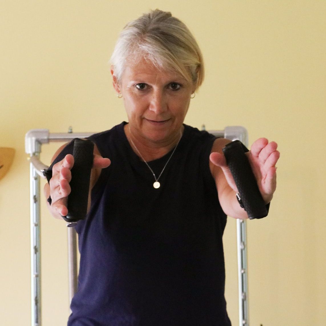a woman in a black shirt is holding a pair of Pilates bands