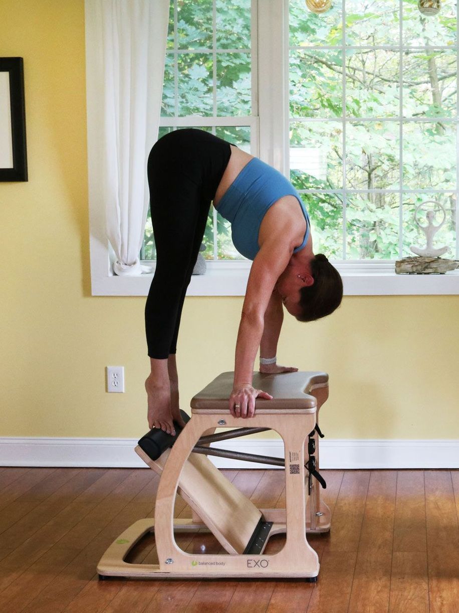a woman is doing a Pilates on a chair in front of a window .
