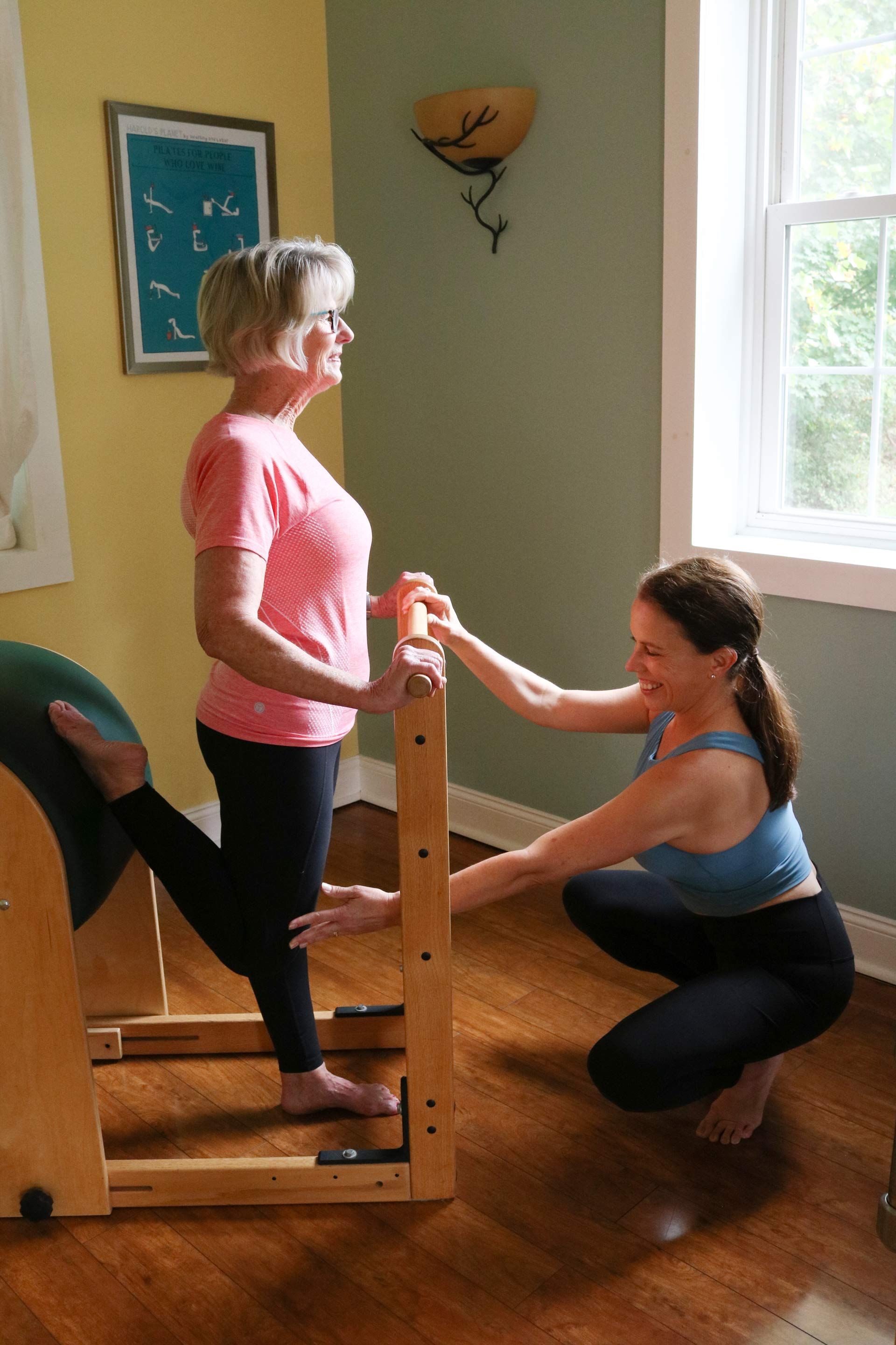 a woman is helping another woman do exercises on a pilates machine .