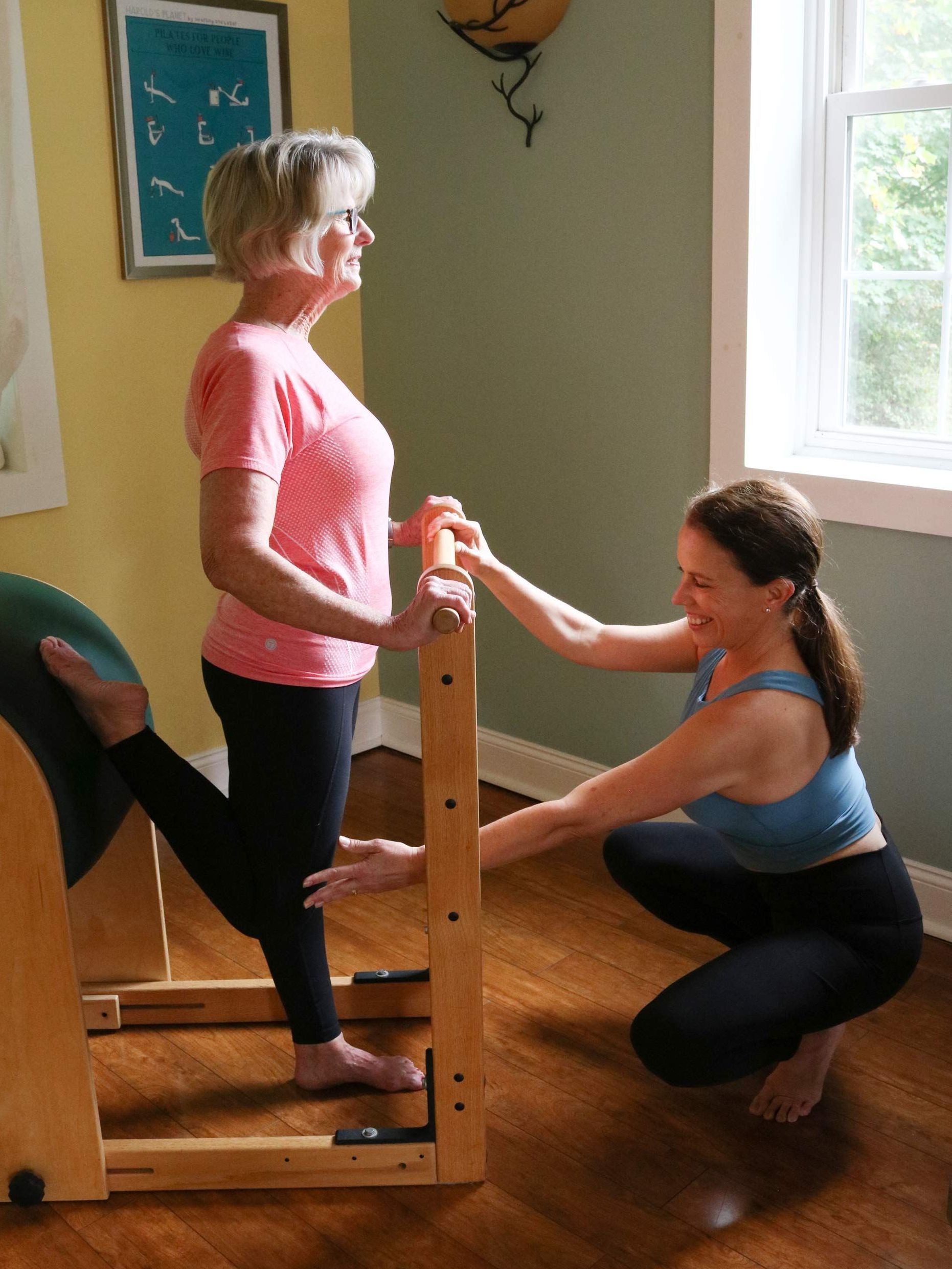 a woman is helping another woman do exercises on a pilates machine .