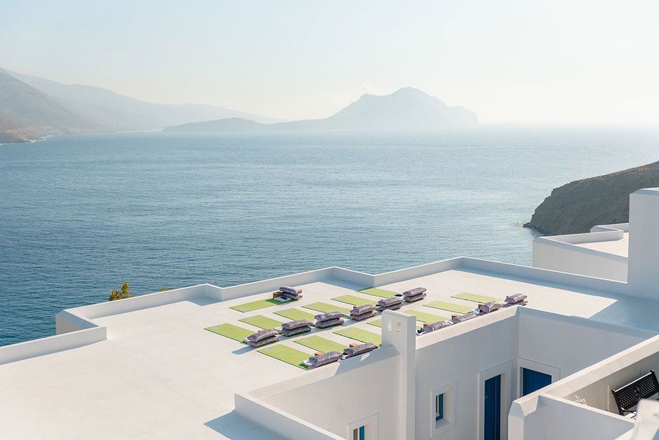 a white building with green chairs on the roof overlooking the ocean .