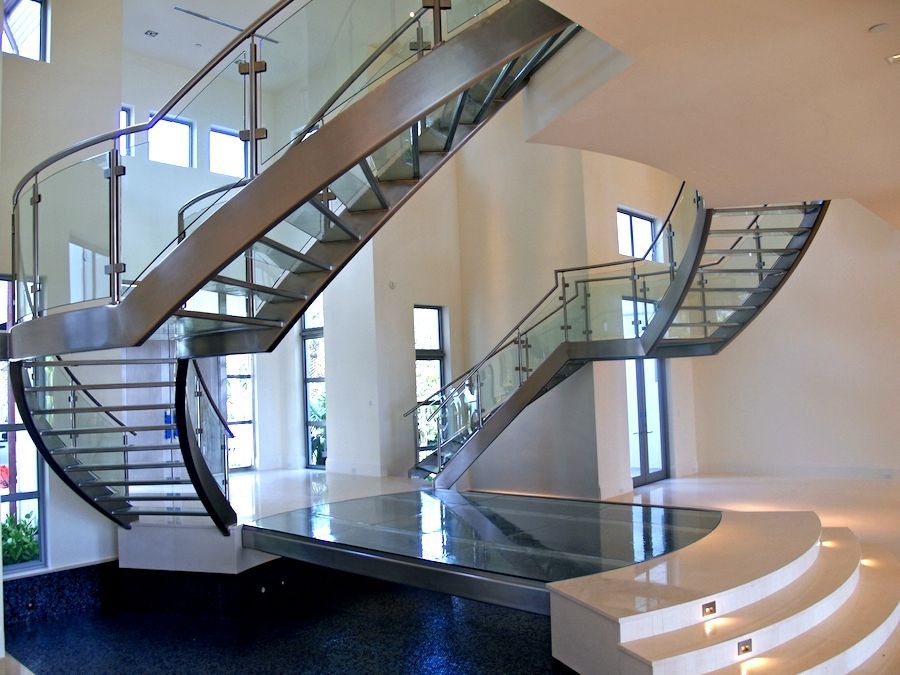 Modern, floating staircase with glass railings and stainless steel accents in a large, bright interior.