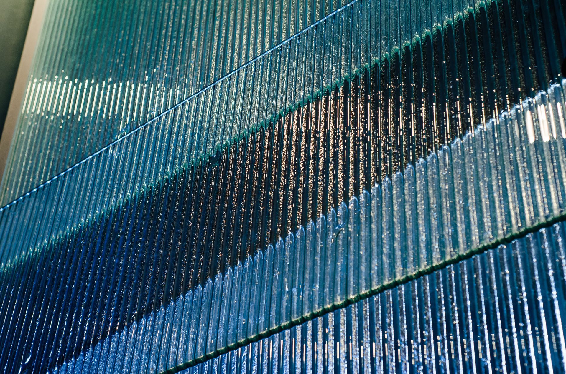 Blue glass wall with diagonal bands of varying shades and texture.
