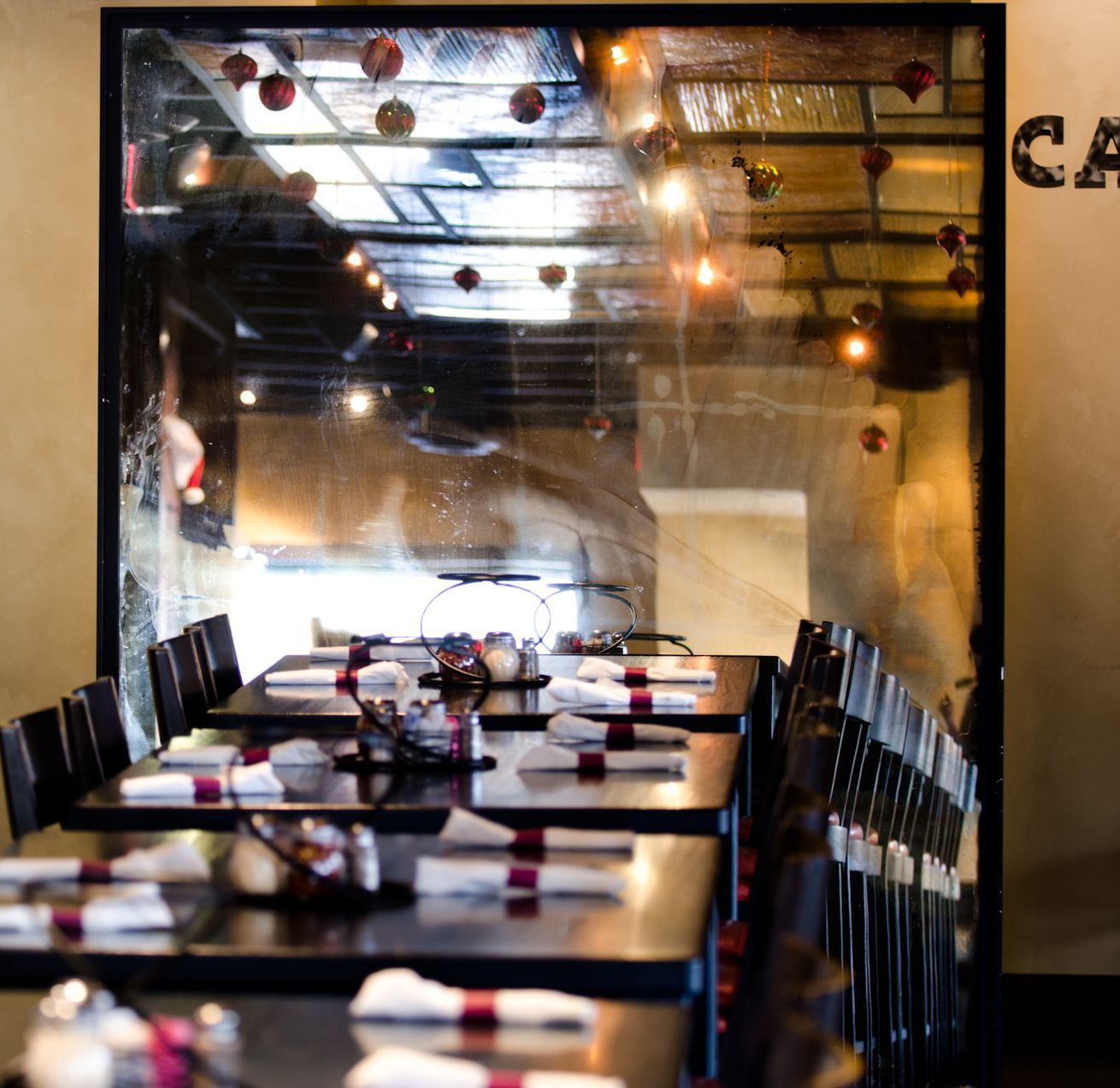 A restaurant with tables and chairs and a sign on the wall that says cu