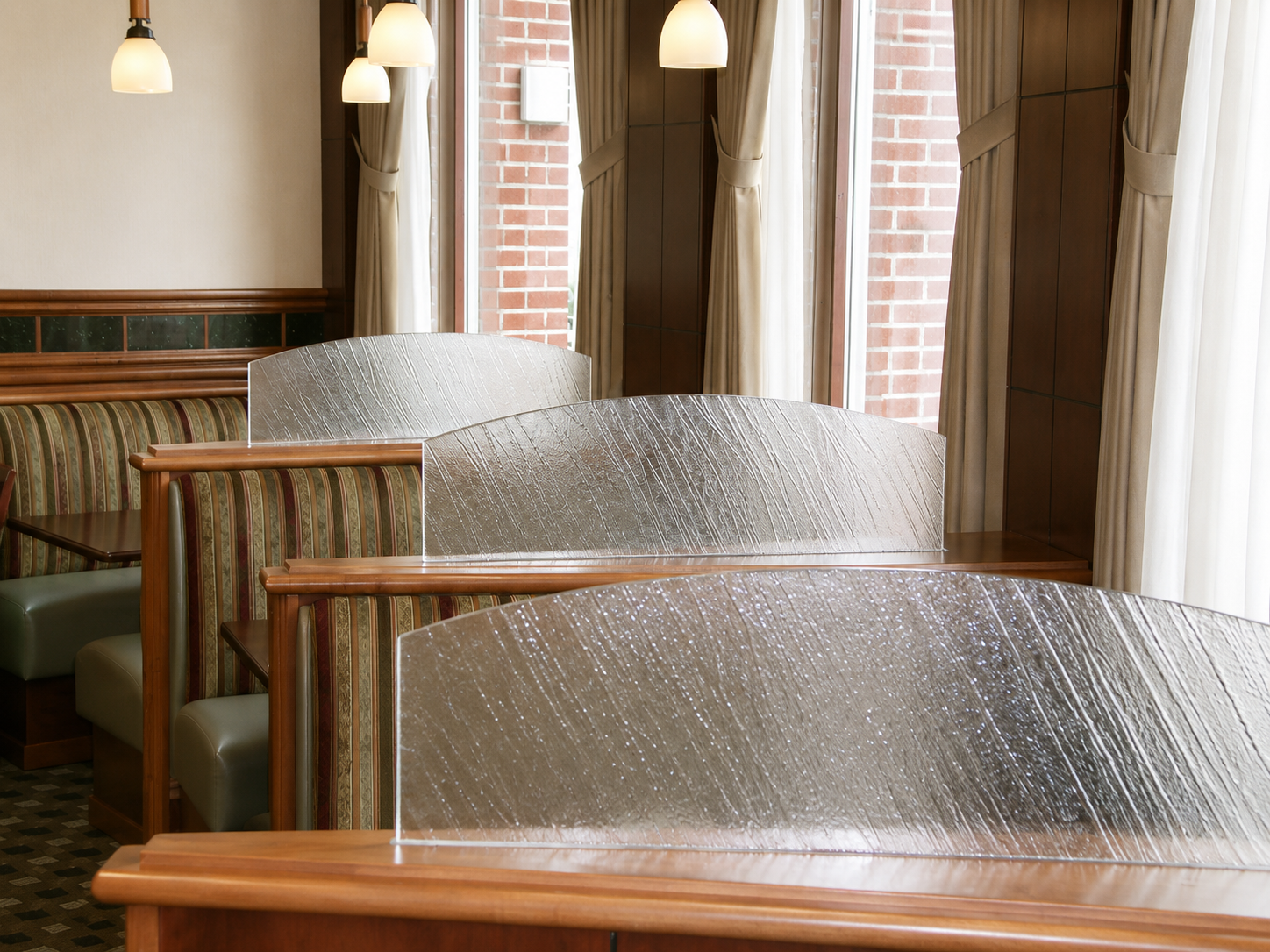 Quiet café seating area with wooden booths, frosted dividers, and hanging lights