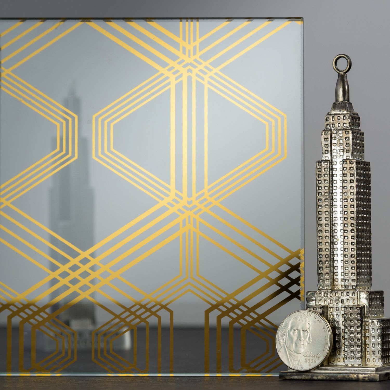 Art Deco glass panel with gold geometric pattern, and Empire State Building statue.