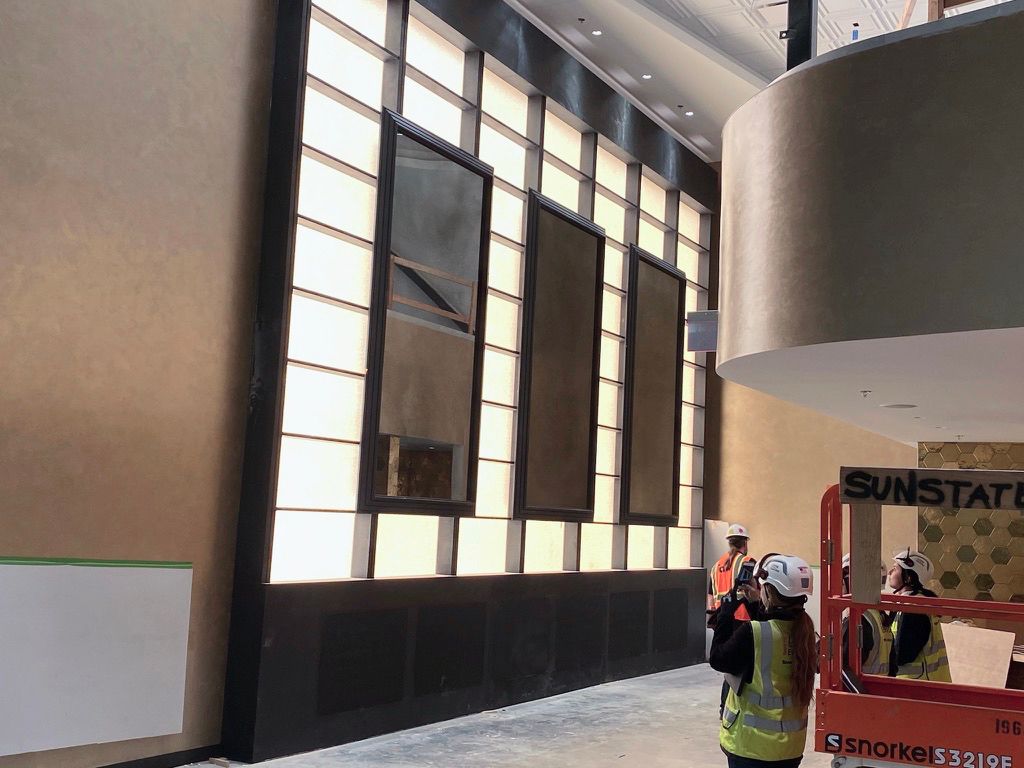 A man is taking a picture of a large antique mirror display in a building.