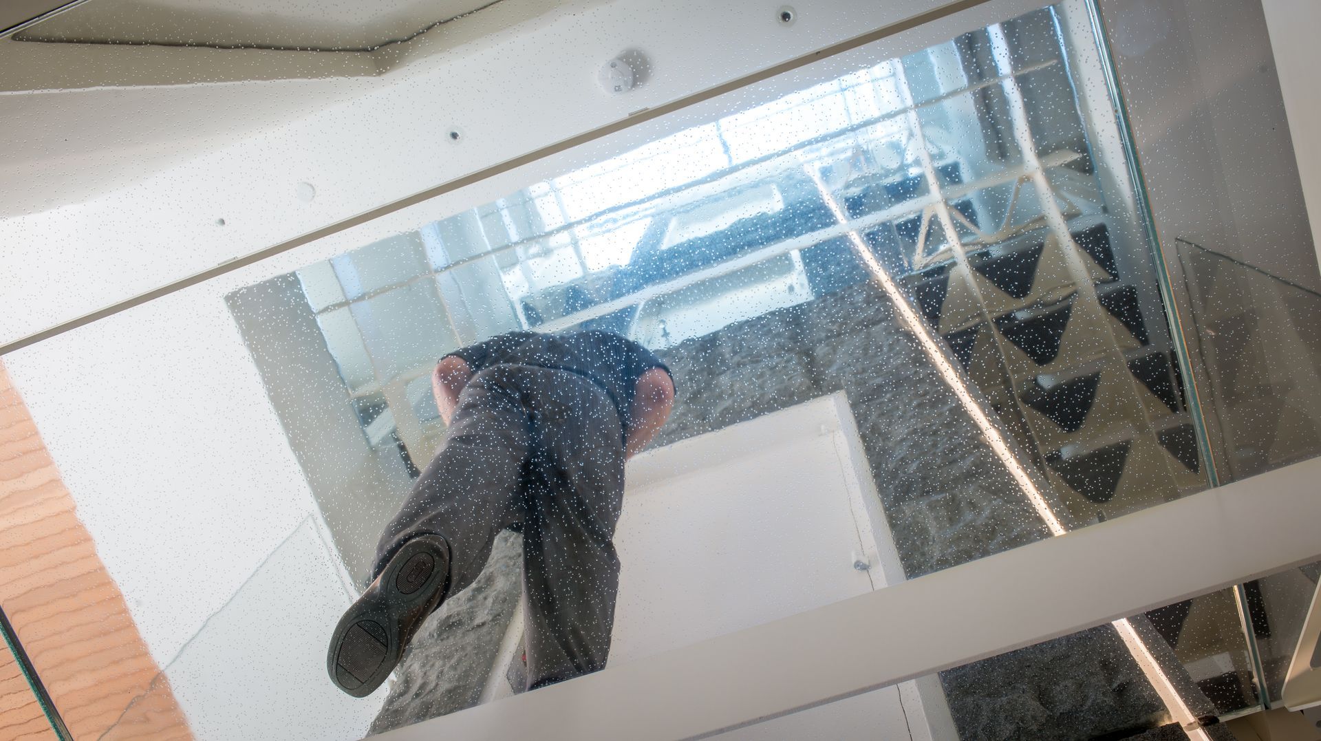 A person falling through the air, surrounded by glass in a modern building.
