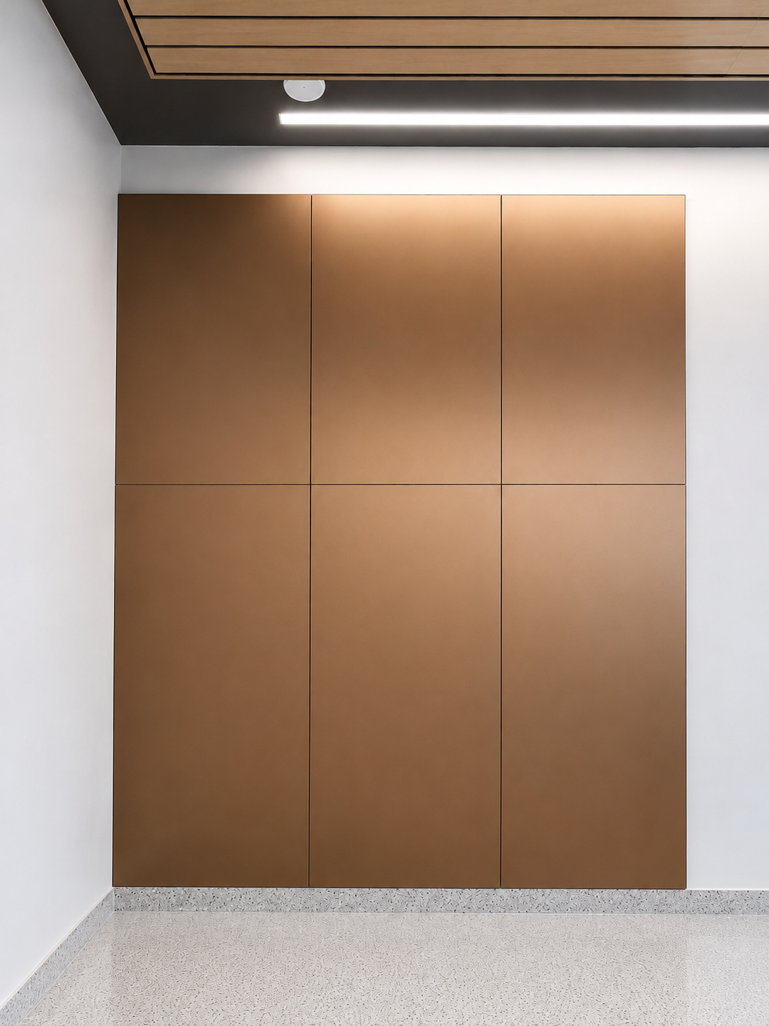 Minimal hallway with a large brown wall cabinet and speckled floor beneath ceiling lights
