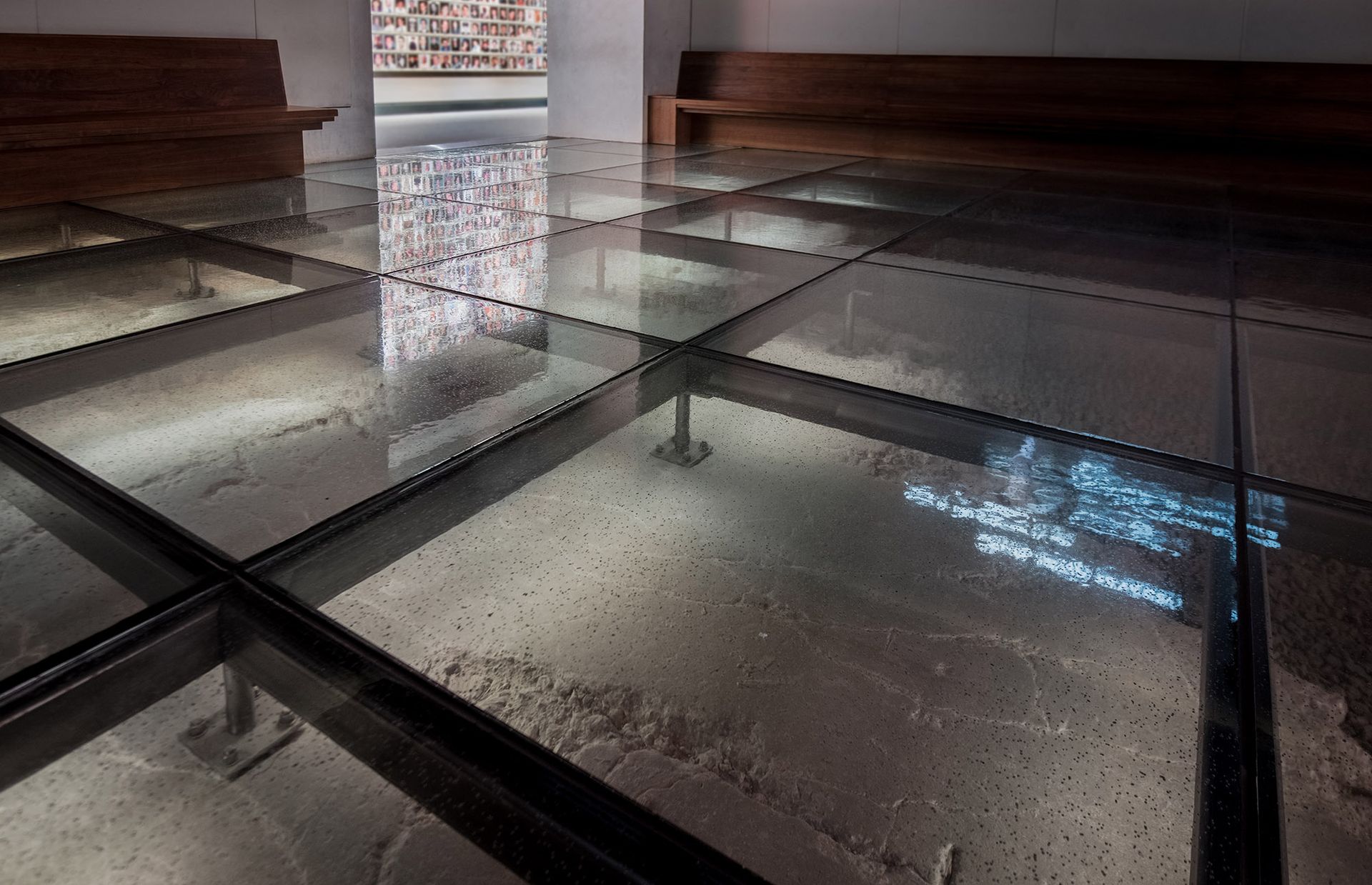 A glass floor in a room with a bench in the background.