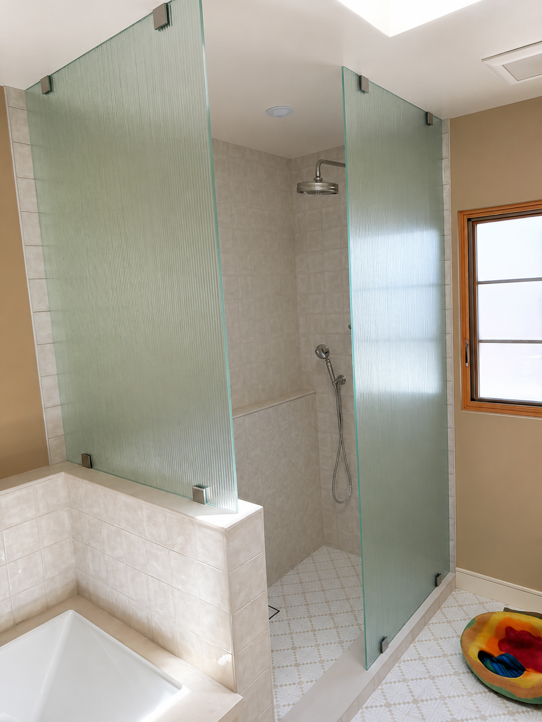 Glass-walled shower with tiled interior and white tub in a bright bathroom