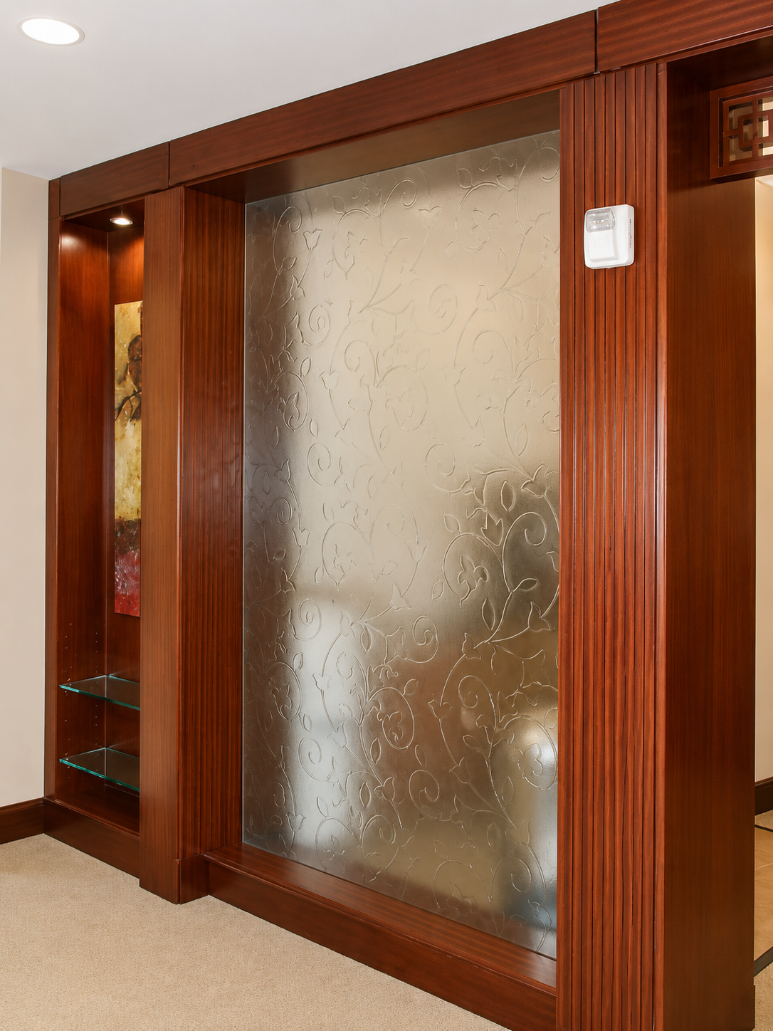 Wood-framed frosted glass sliding door in a hallway with beige carpet and warm wood trim