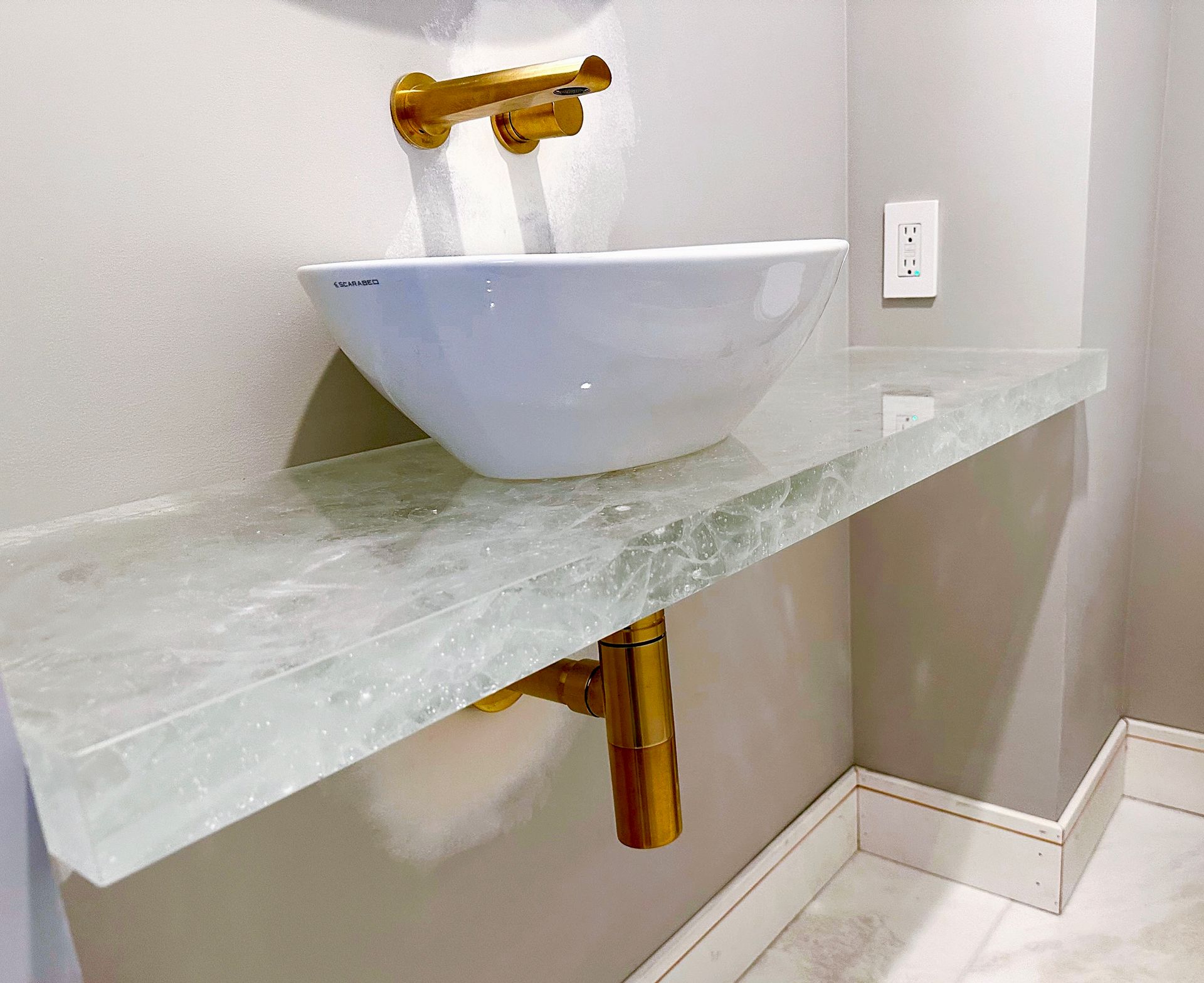 A bathroom with a sink and a glass counter top.