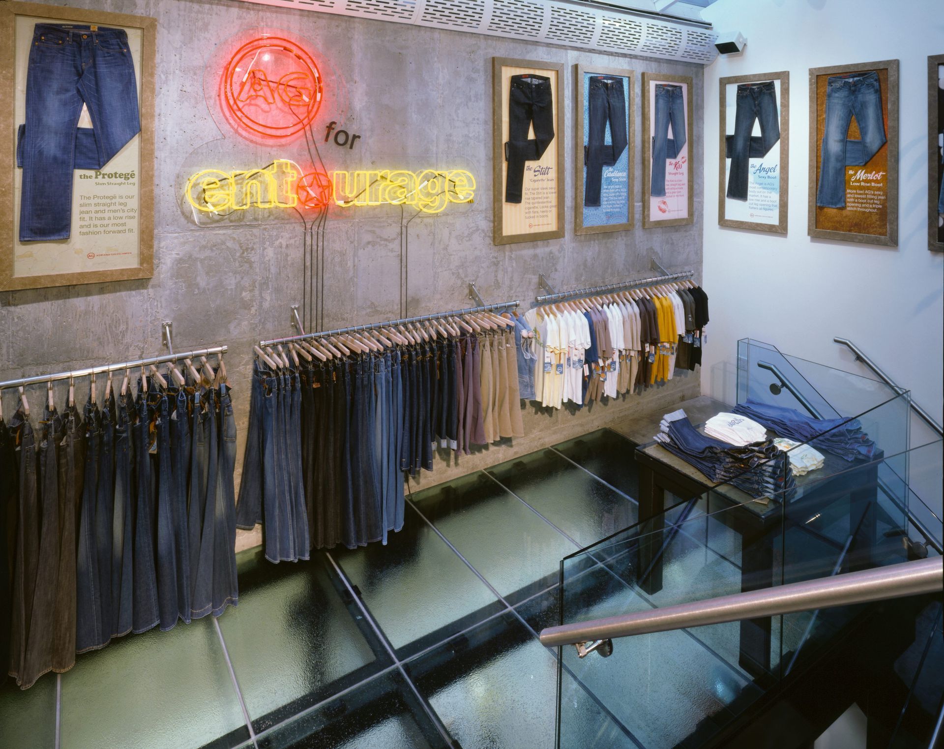 Jeans display in a clothing store with neon sign and glass flooring.