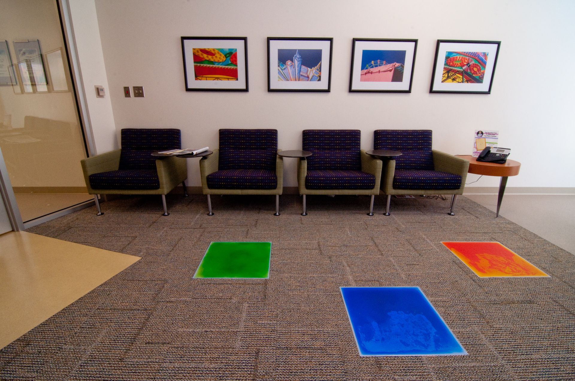 A waiting room with chairs and colorful liquid lava squares on the floor.