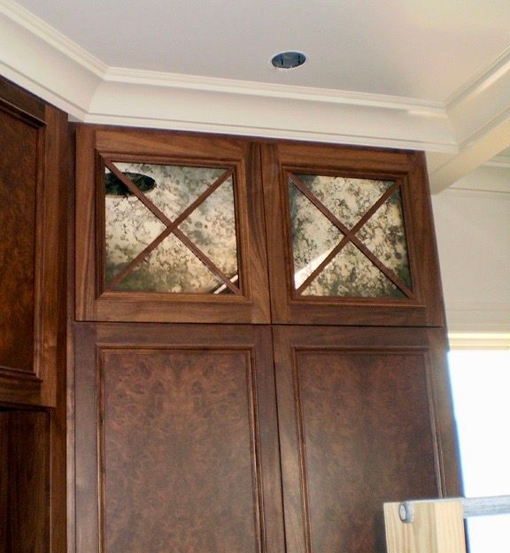 A kitchen with wooden cabinets with antique mirror inlay