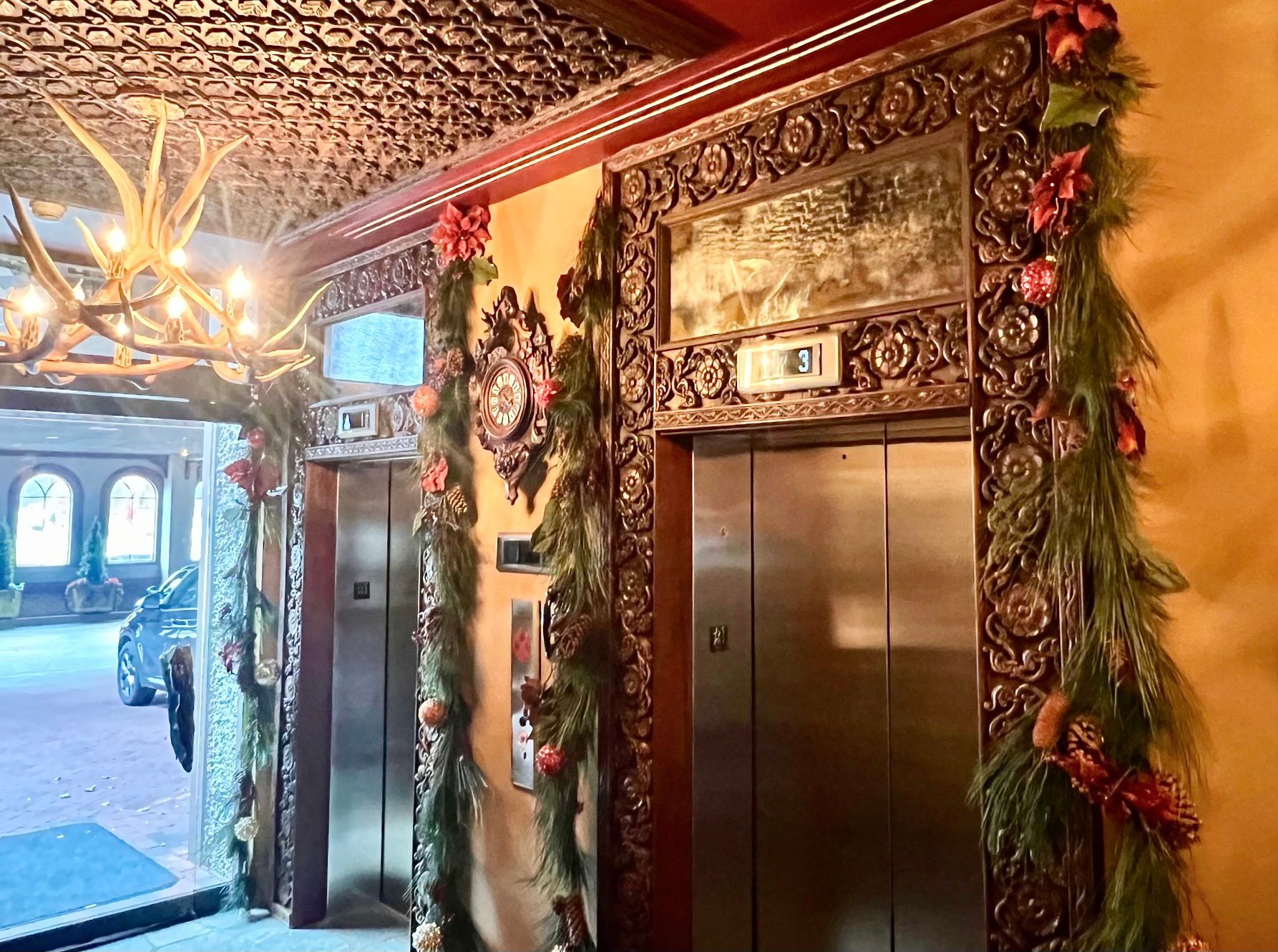 Two elevators in a building decorated for christmas.