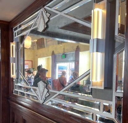 A group of people at Hollywood Studios sitting in front of a antique mirror in a restaurant.