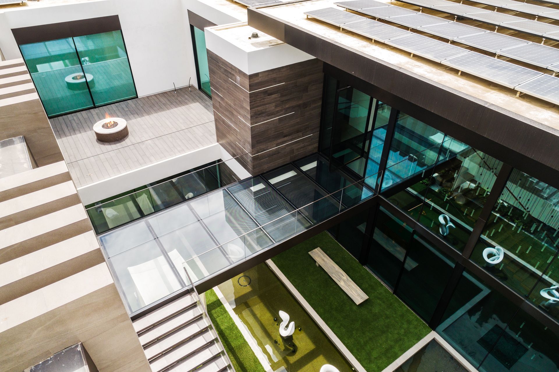 Modern atrium with glass walkways, green courtyard, and teal doors in a contemporary building