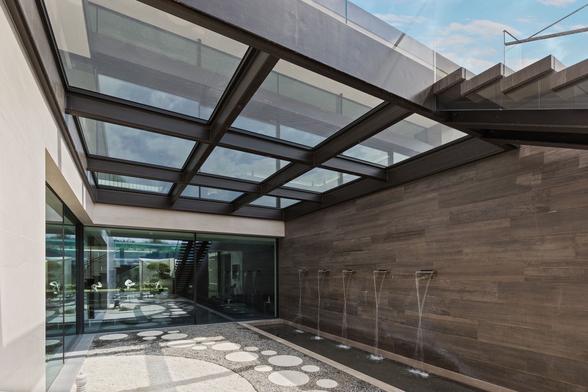 Modern building entrance with glass canopy, stone wall, and patterned walkway
