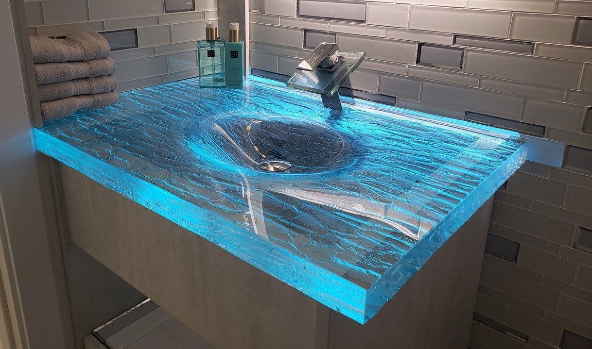 A glass sink backlit with blue LED lights.