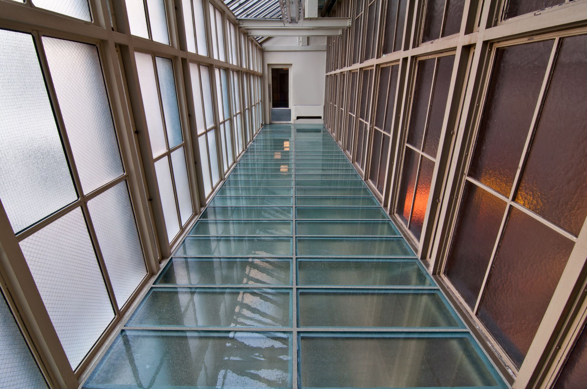 Glass floor walkway with windows on either side.