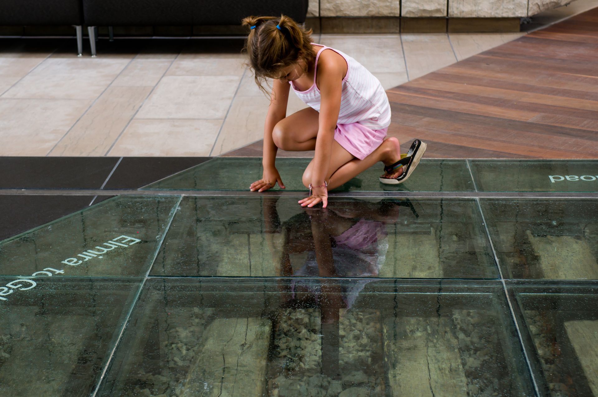 A girl crouching on a custom glass floor.