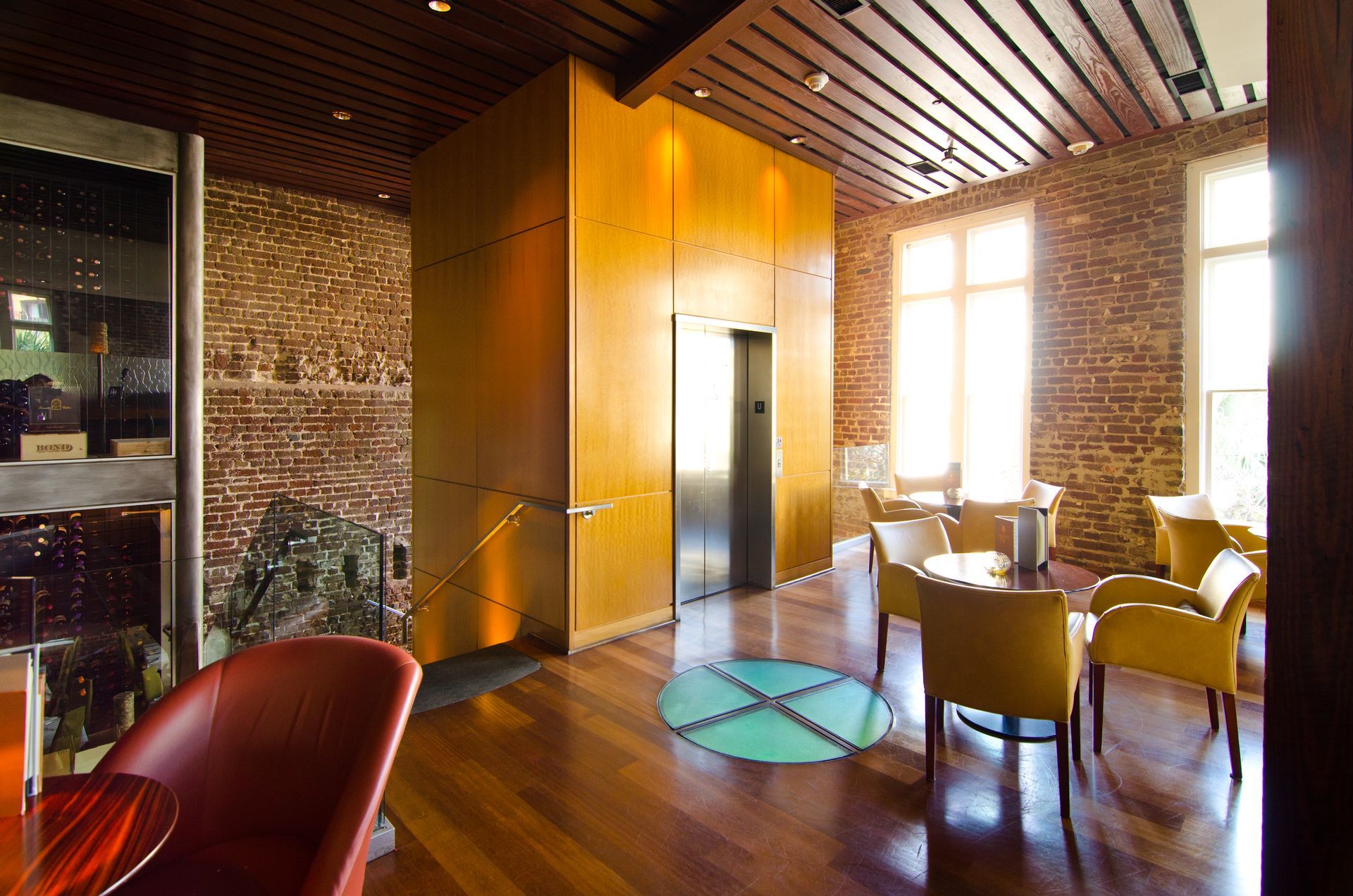 A room with tables and chairs and a brick wall with a glass floor feature