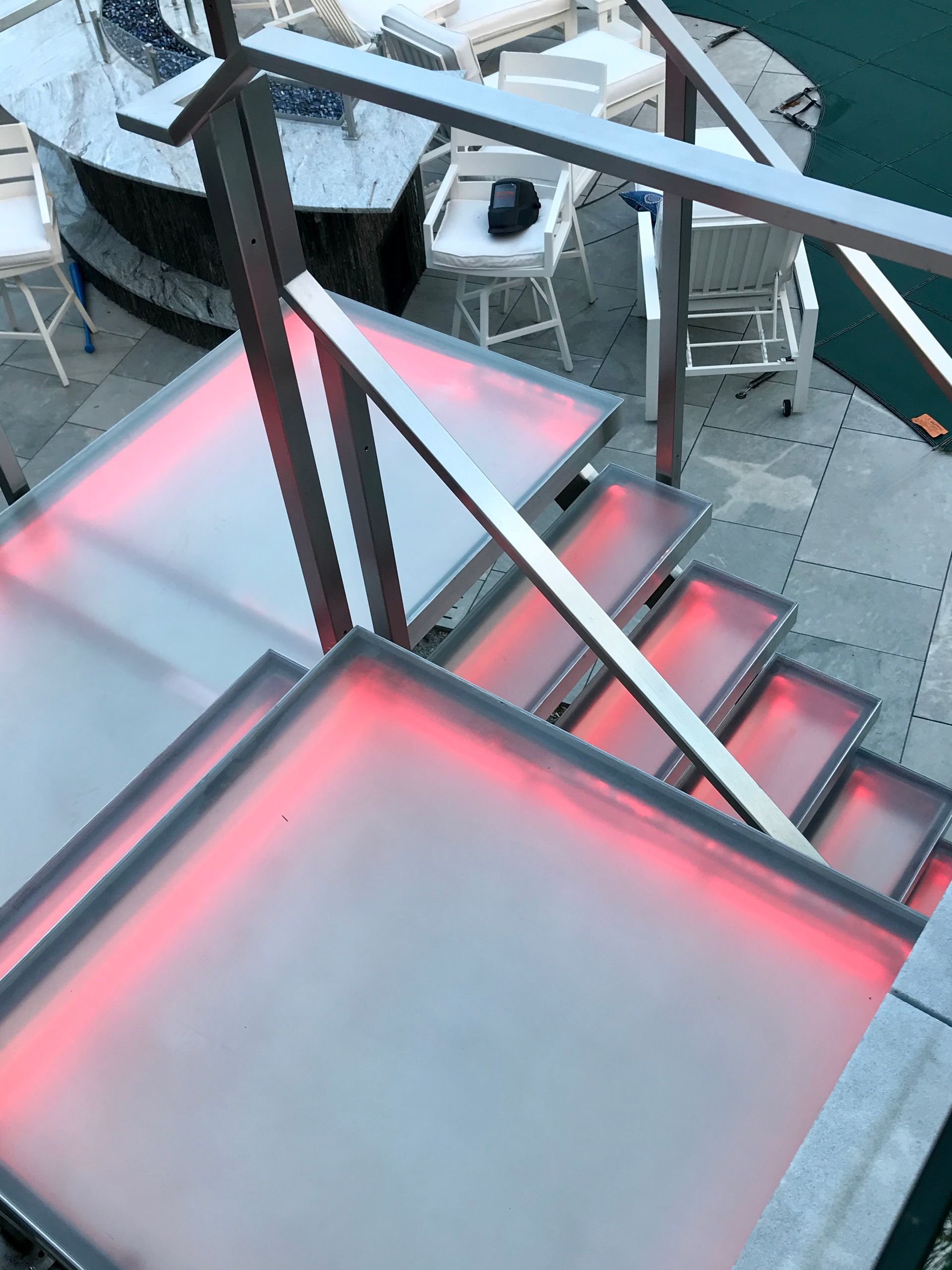 Custom glass stairs and treads with integrated pink LED lighting.