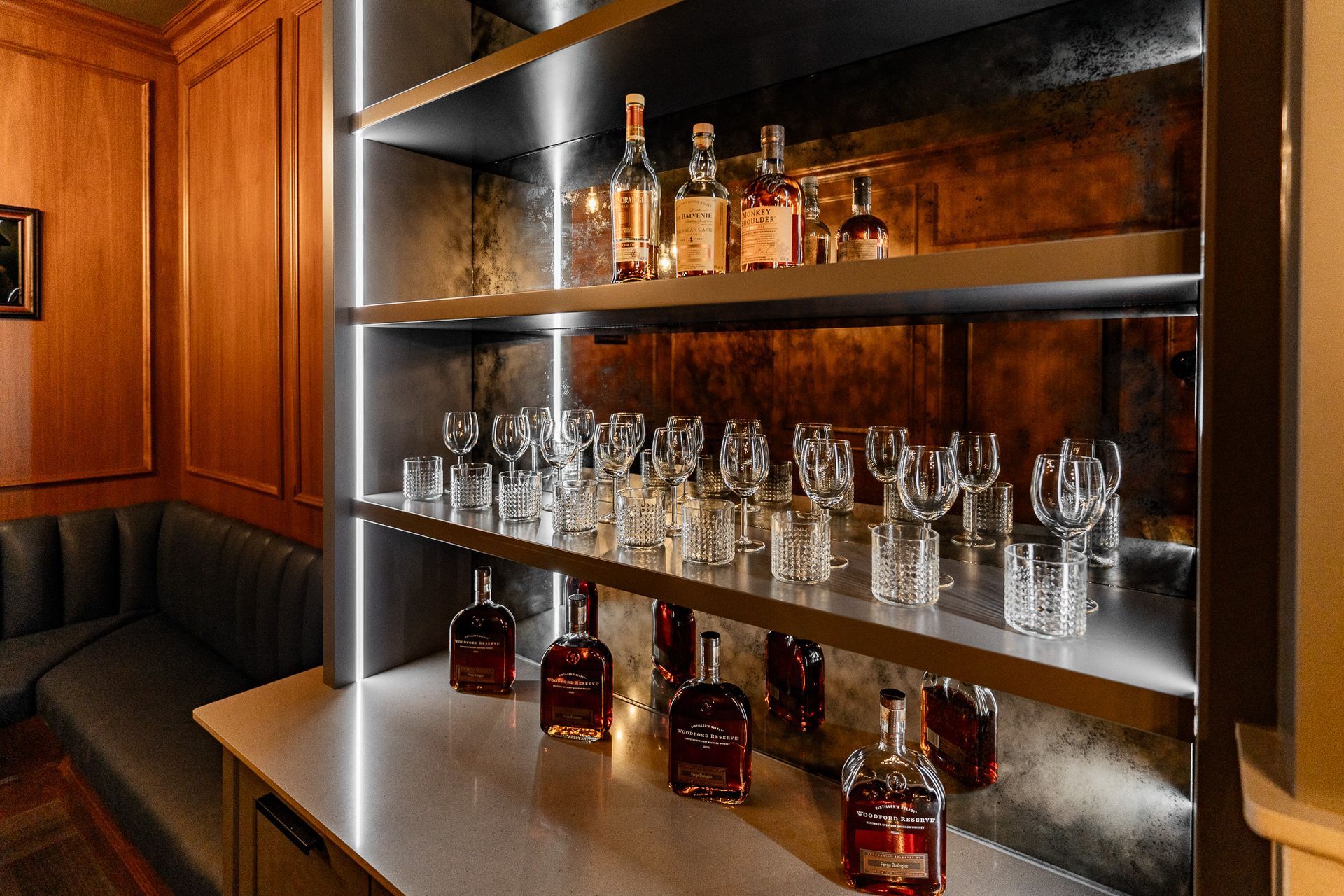 A bar with bottles of whiskey and glasses on shelves.