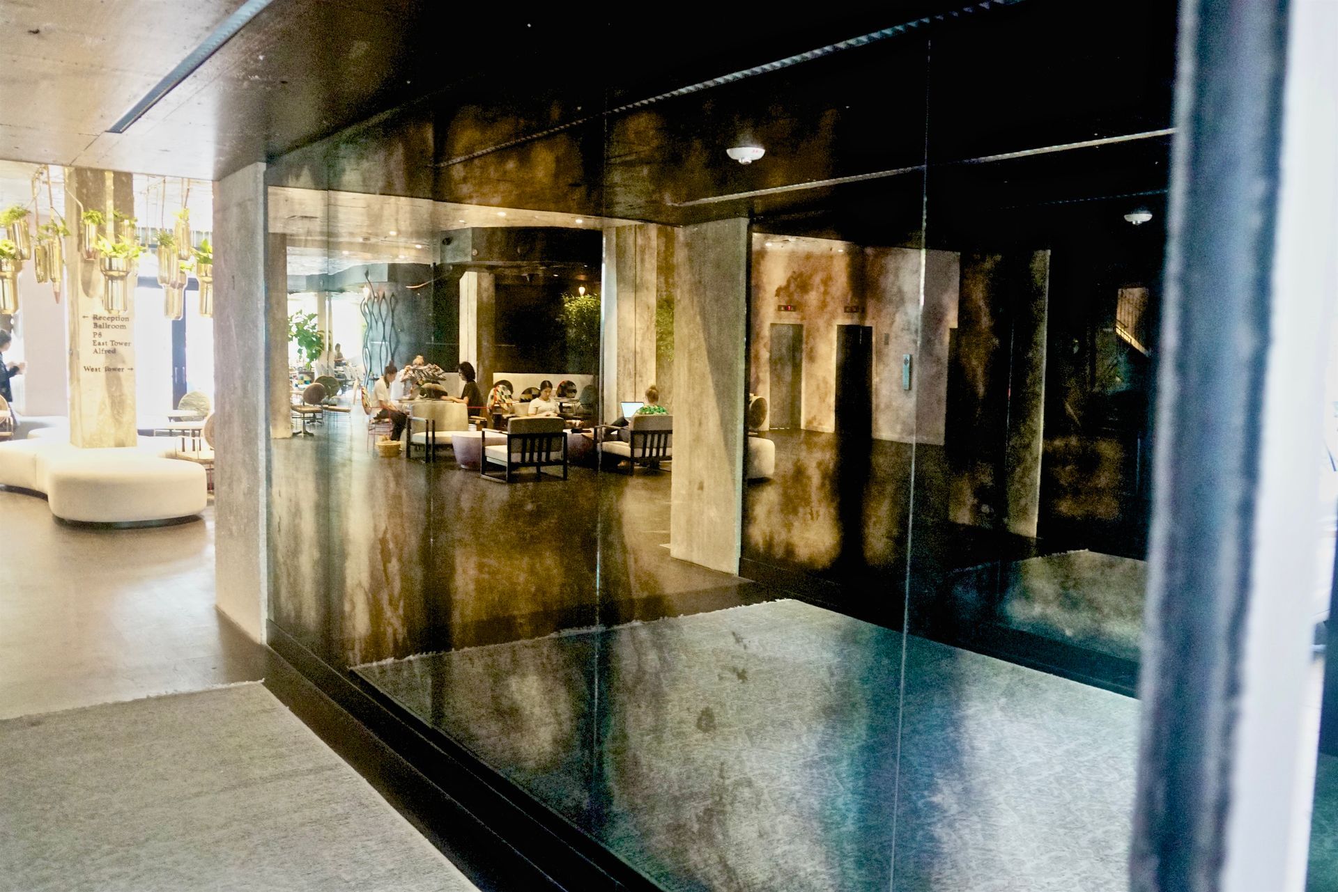 A dark-walled lobby with mirrored walls. People sit at tables, reflected in the mirrors.