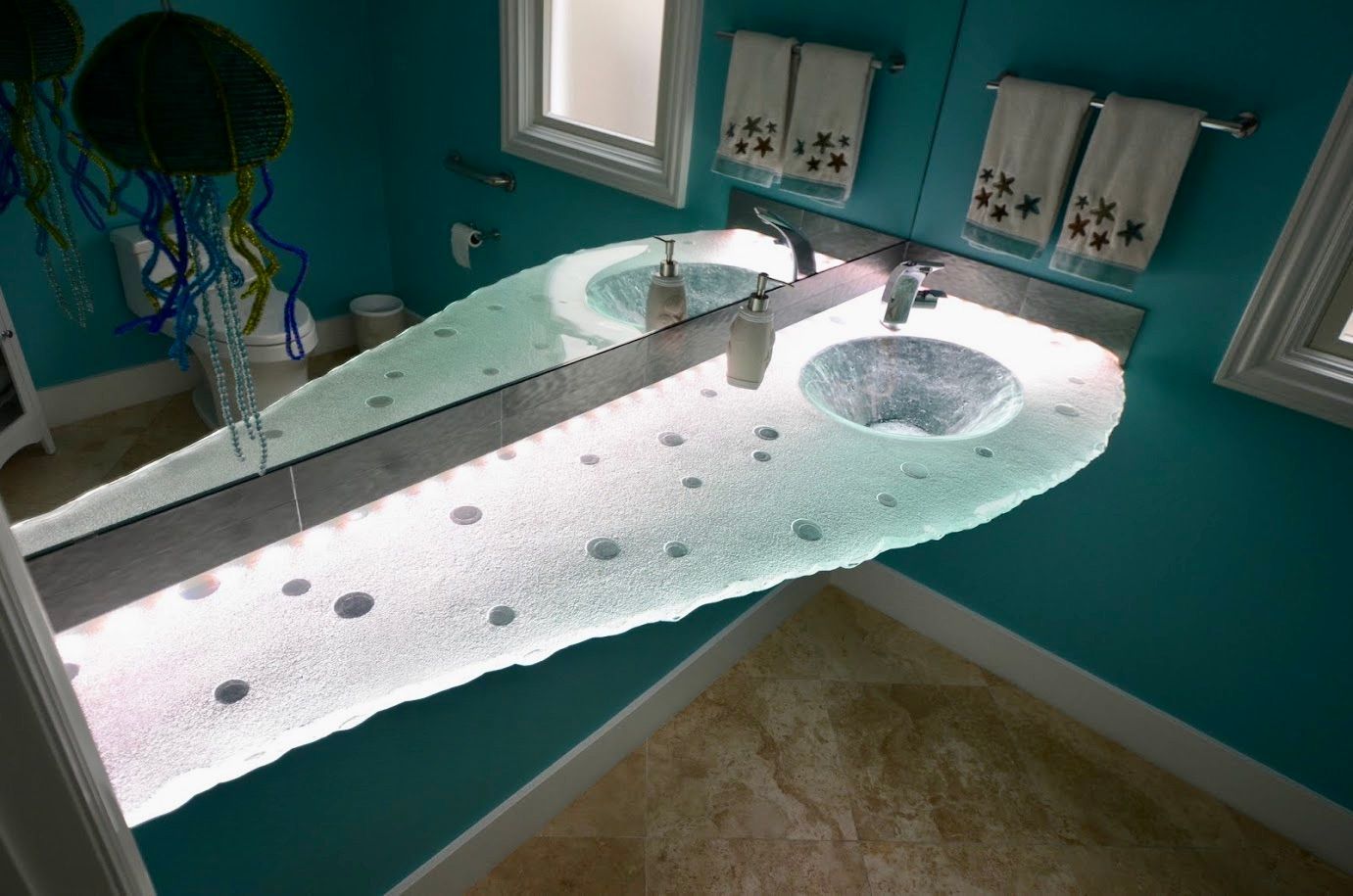 A bathroom with glass counter top and sink