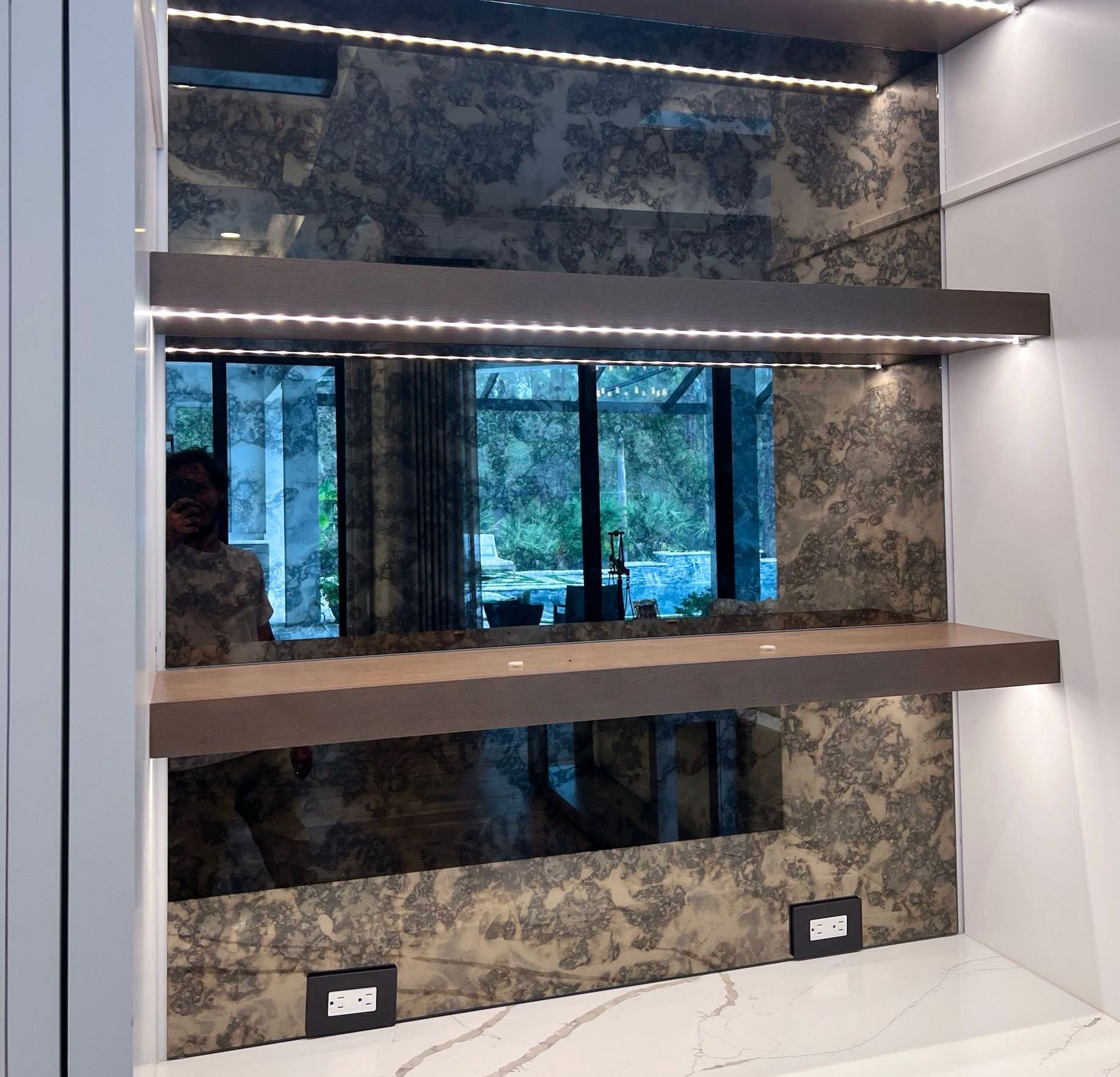 A shelf in a room with an antique mirror behind it
