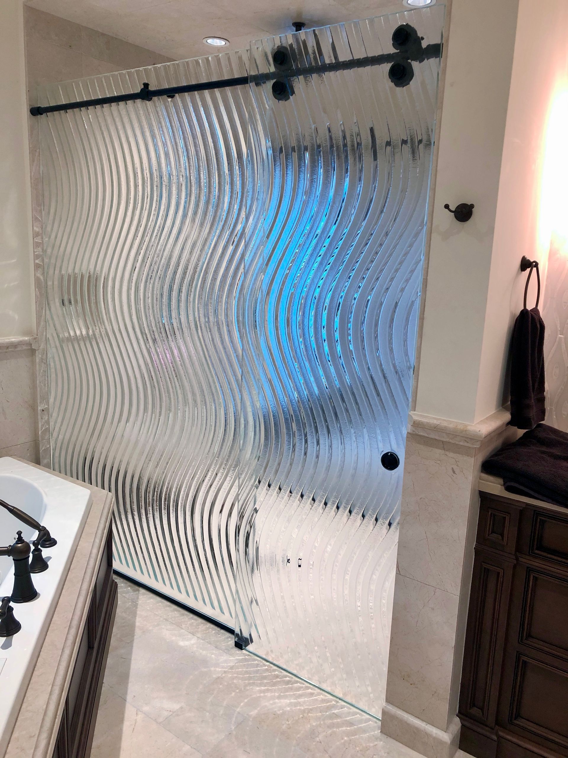 Textured glass shower door in a bathroom with a sliding track.