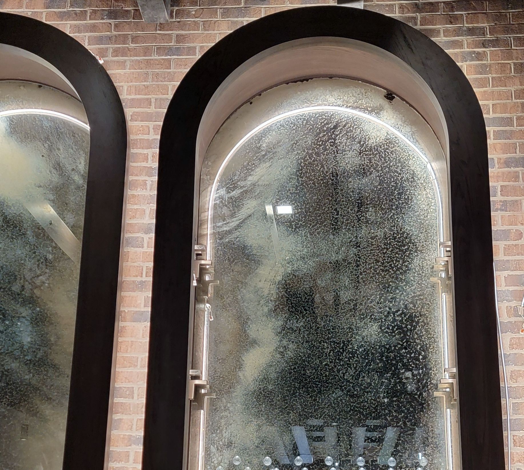 Three arched windows with a brick wall behind them