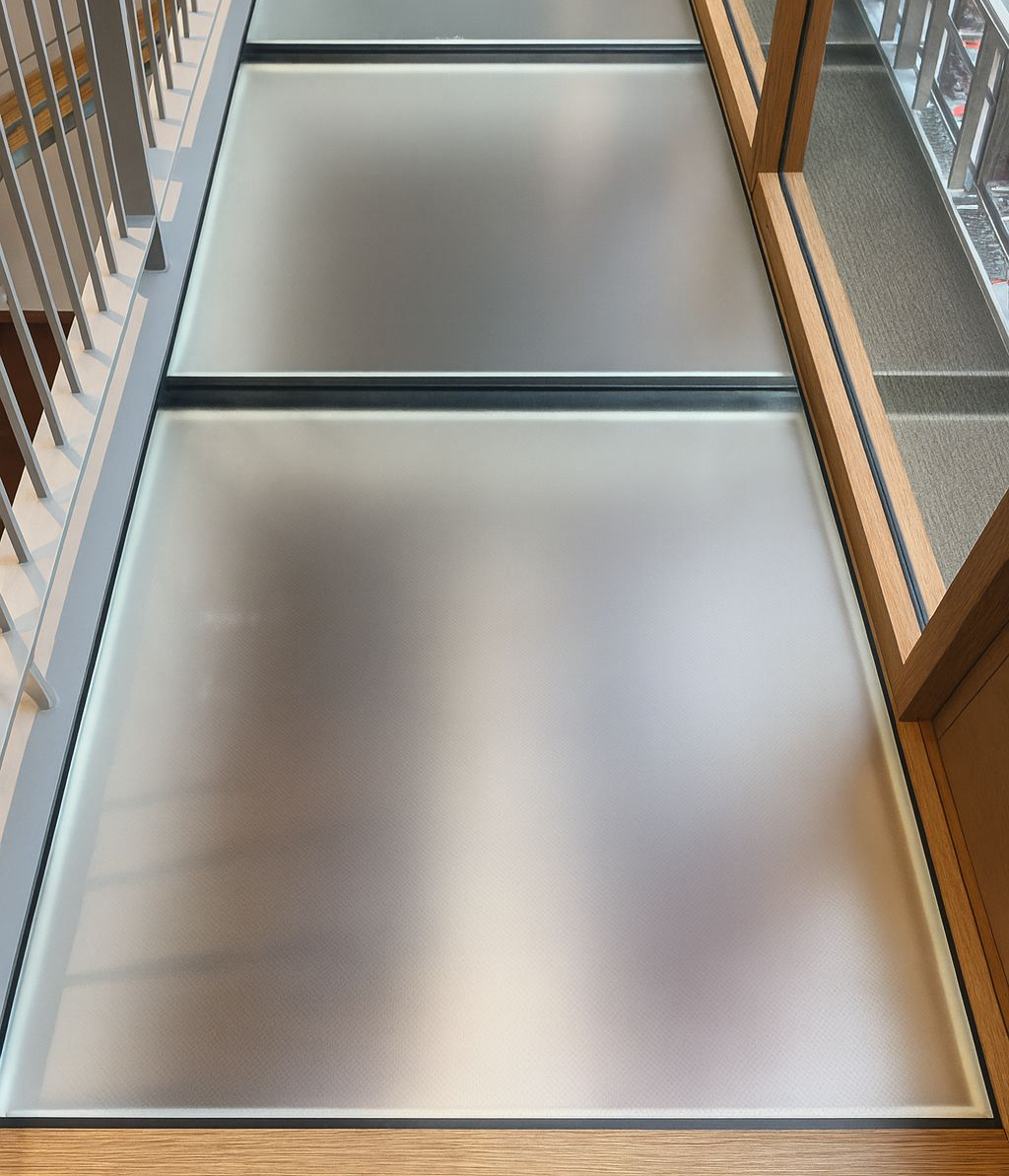 Glass floor panels in a building, framed in black. The panels appear frosted.