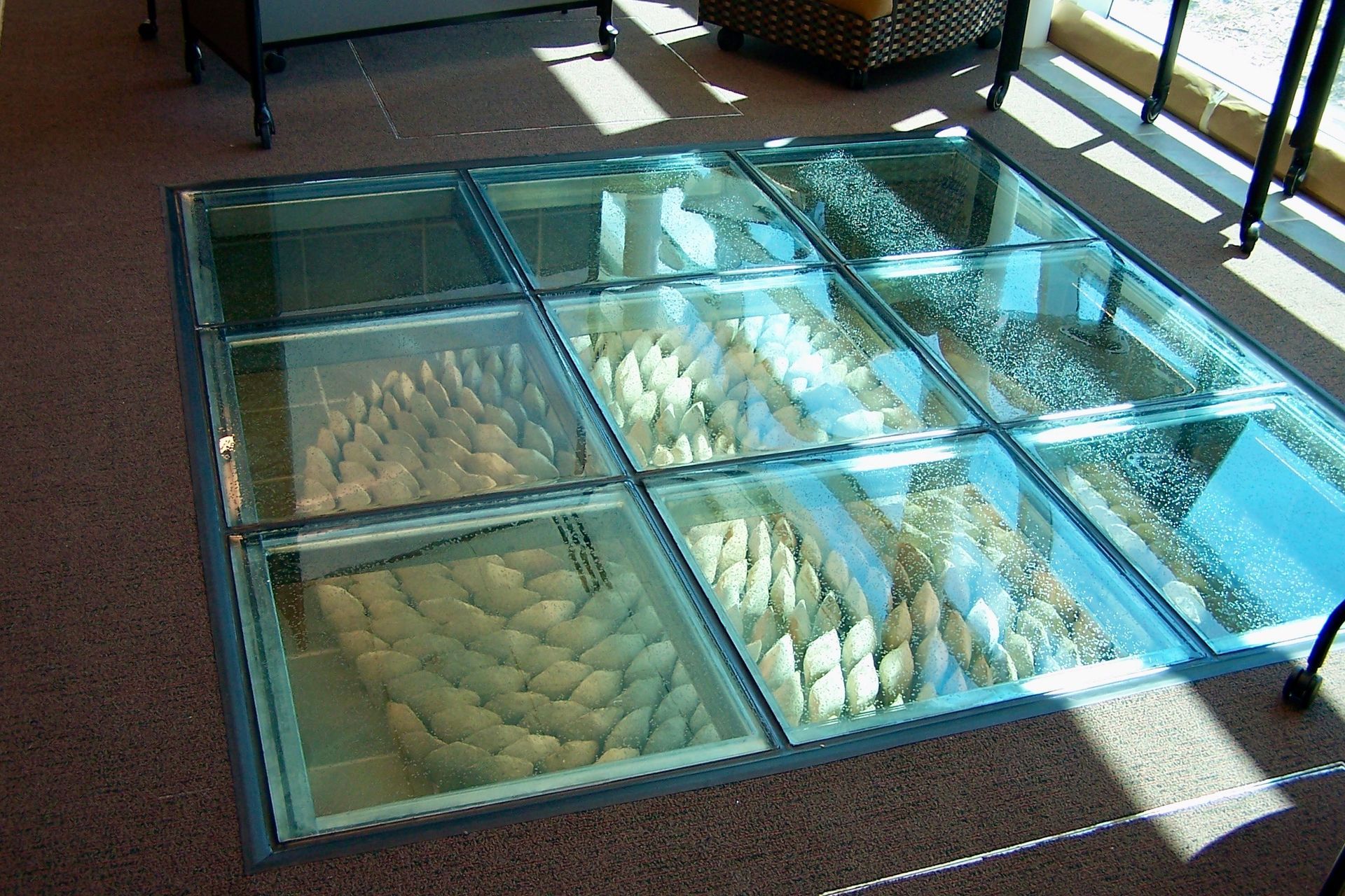 Glass floor display with woven baskets or loaves arranged in compartments beneath a walkway