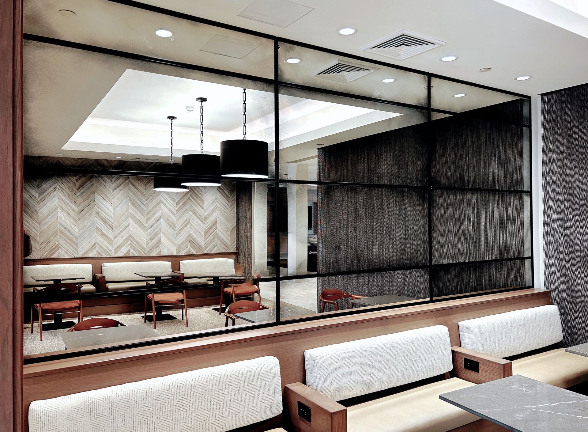 A restaurant with tables and benches and a large antique mirror on the wall.