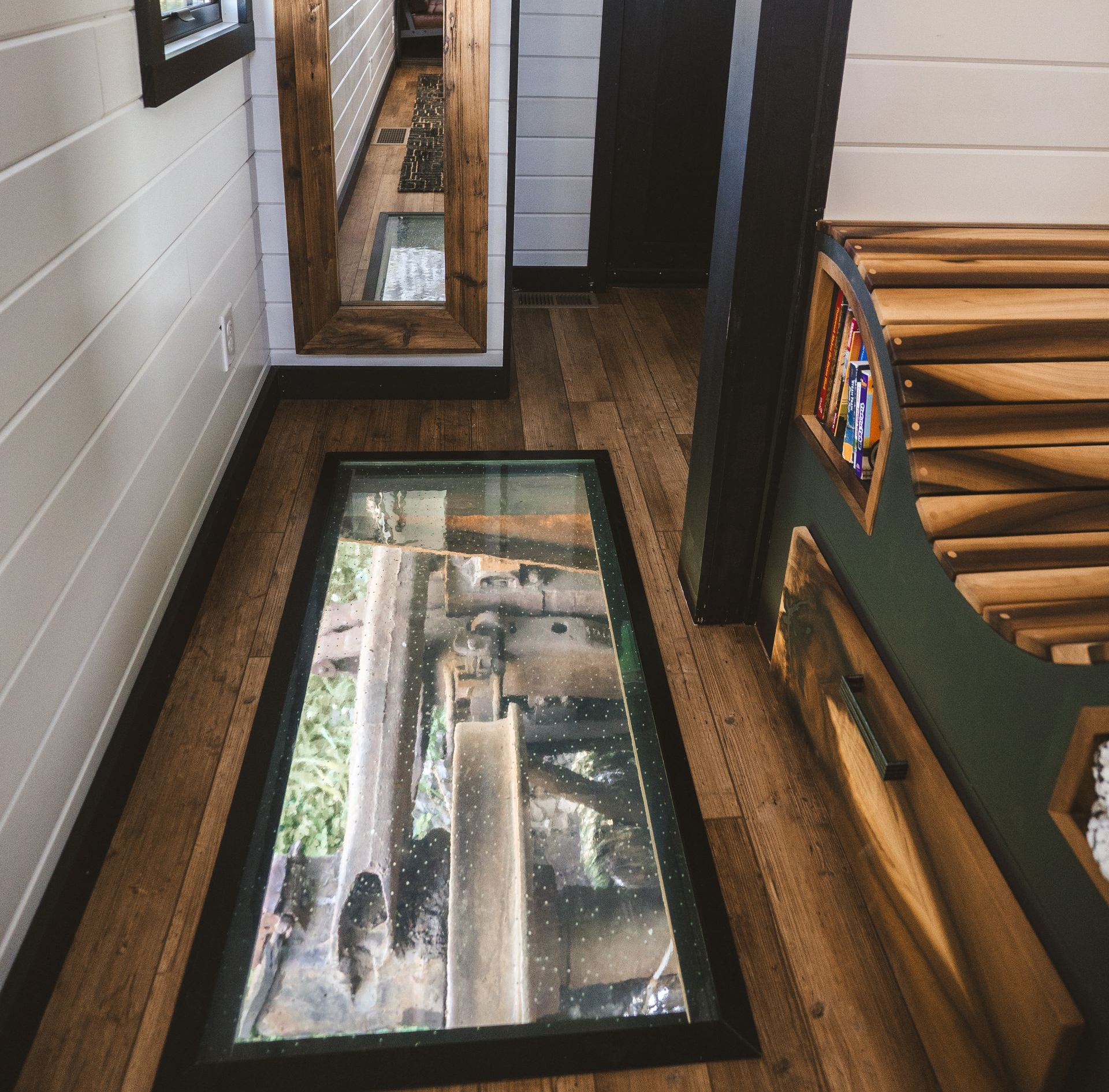 Wooden-floored interior with glass-paneled floor revealing machinery below. Wooden accents and white-paneled walls.