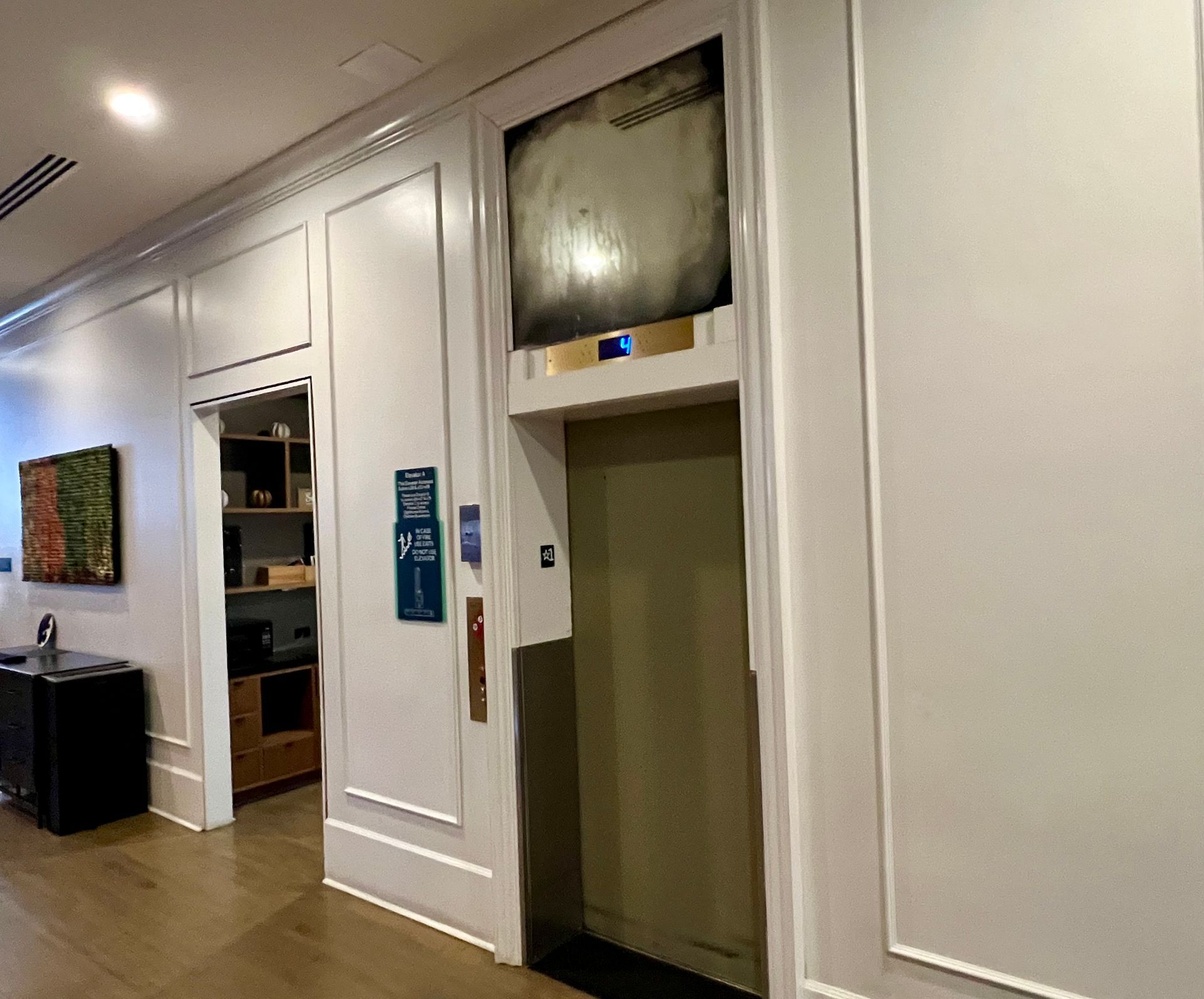 There is an elevator in the middle of a hallwa, featuring an antique mirror