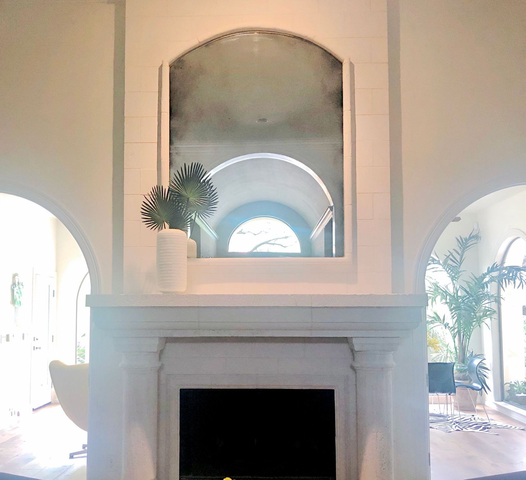 A fireplace with an antique mirror above it in a living room
